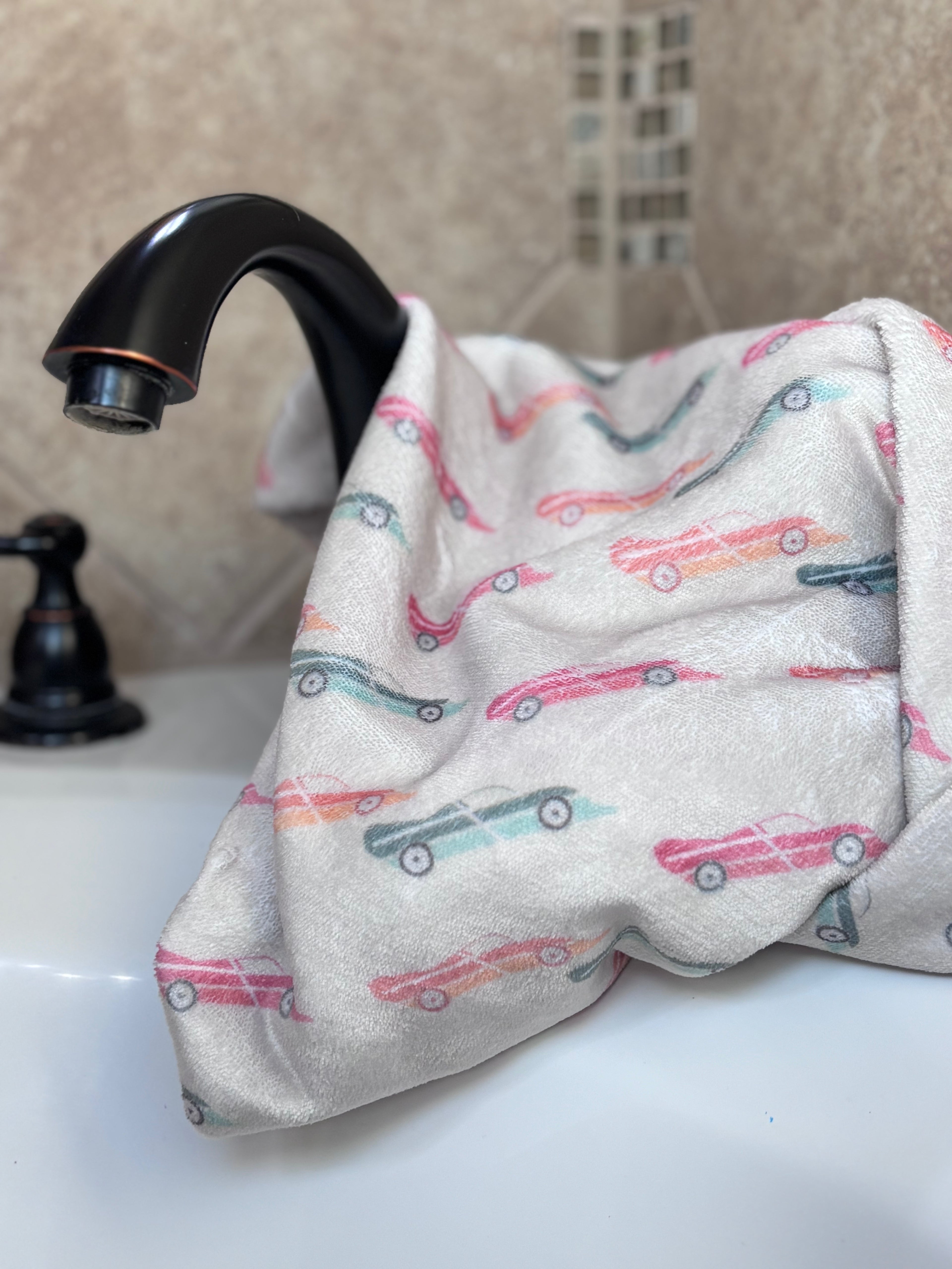 racing toy cars hooded baby towel displayed on a bathtub faucet