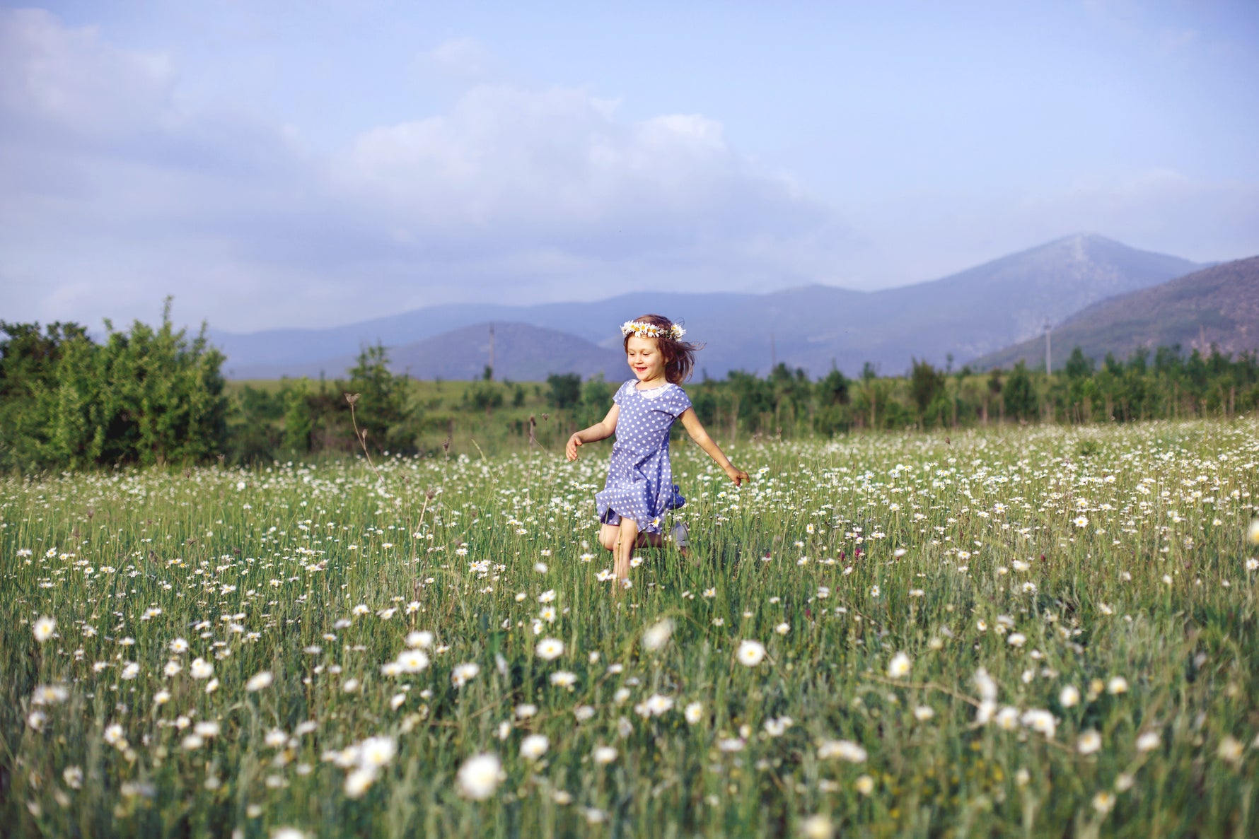 girl running through field of daisies