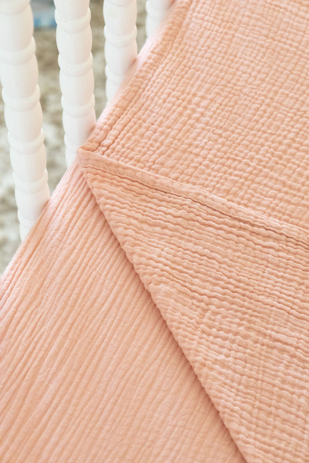 Close-up of textured peach fabric with white spindle background