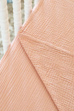 Close-up of a textured peach fabric with a blurred white background