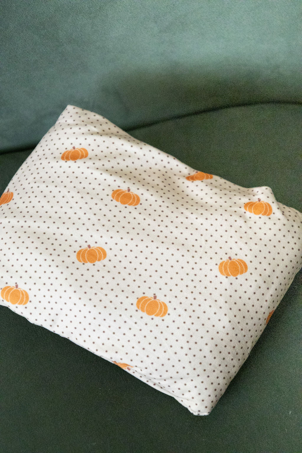 Fabric with small orange pumpkins pattern on a green surface
