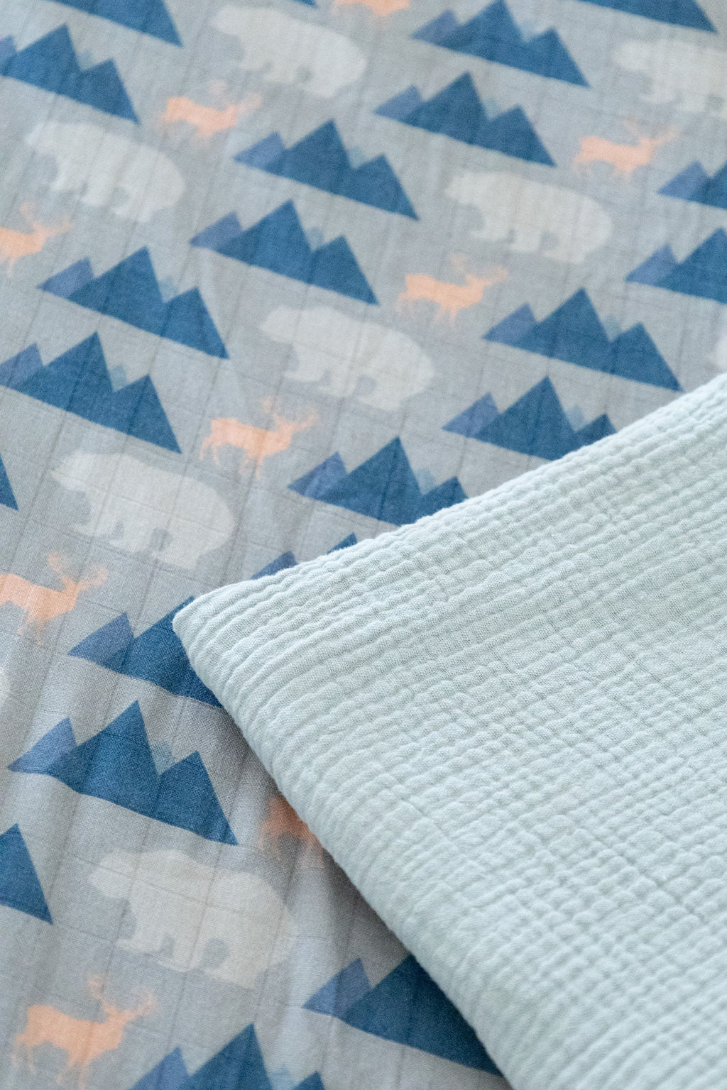 Close-up of a quilt with blue geometric patterns and a textured light blue border.