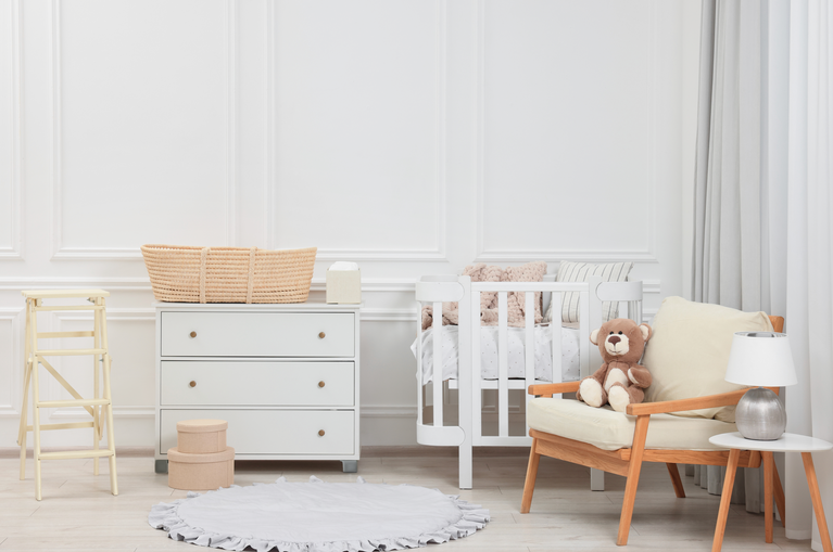 Nursery room with crib, chair, and teddy bear.