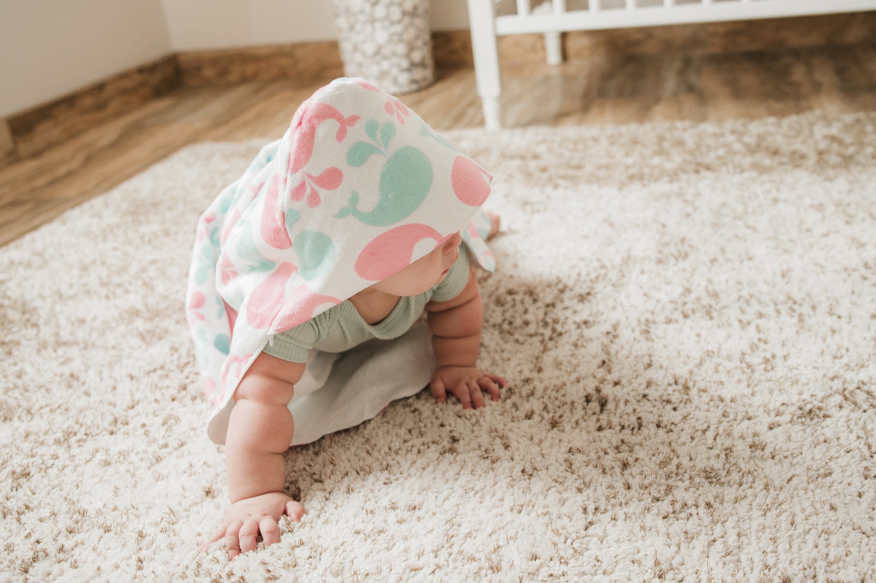 Baby in a whale themed hooded towel on a carpeted floor